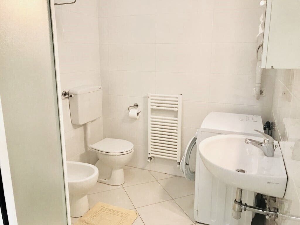Un baño pequeño y limpio con inodoro, lavamanos y radiador.