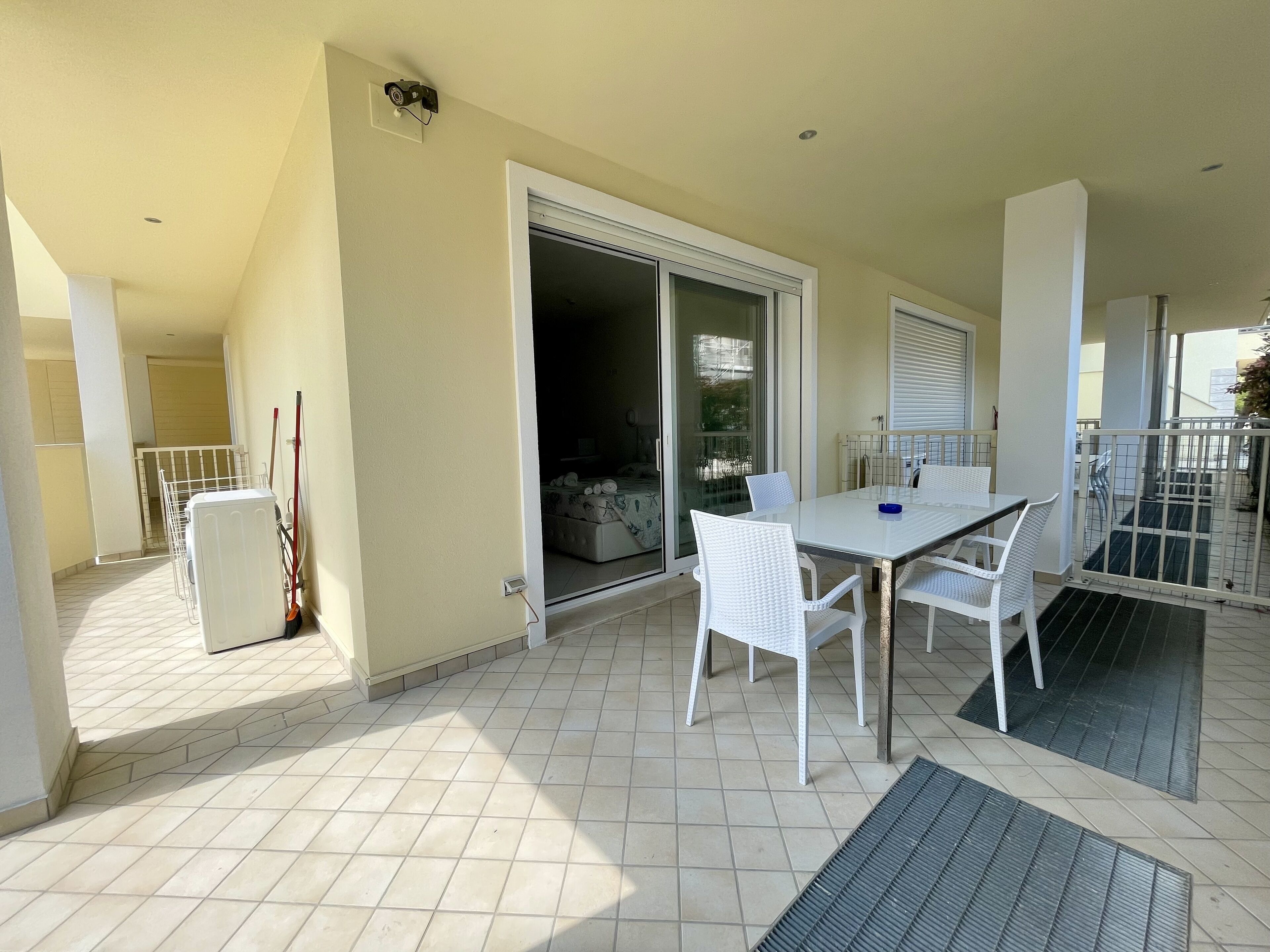 Un balcon avec une table et des chaises, une porte-fenêtre coulissante et une vue sur l’intérieur.