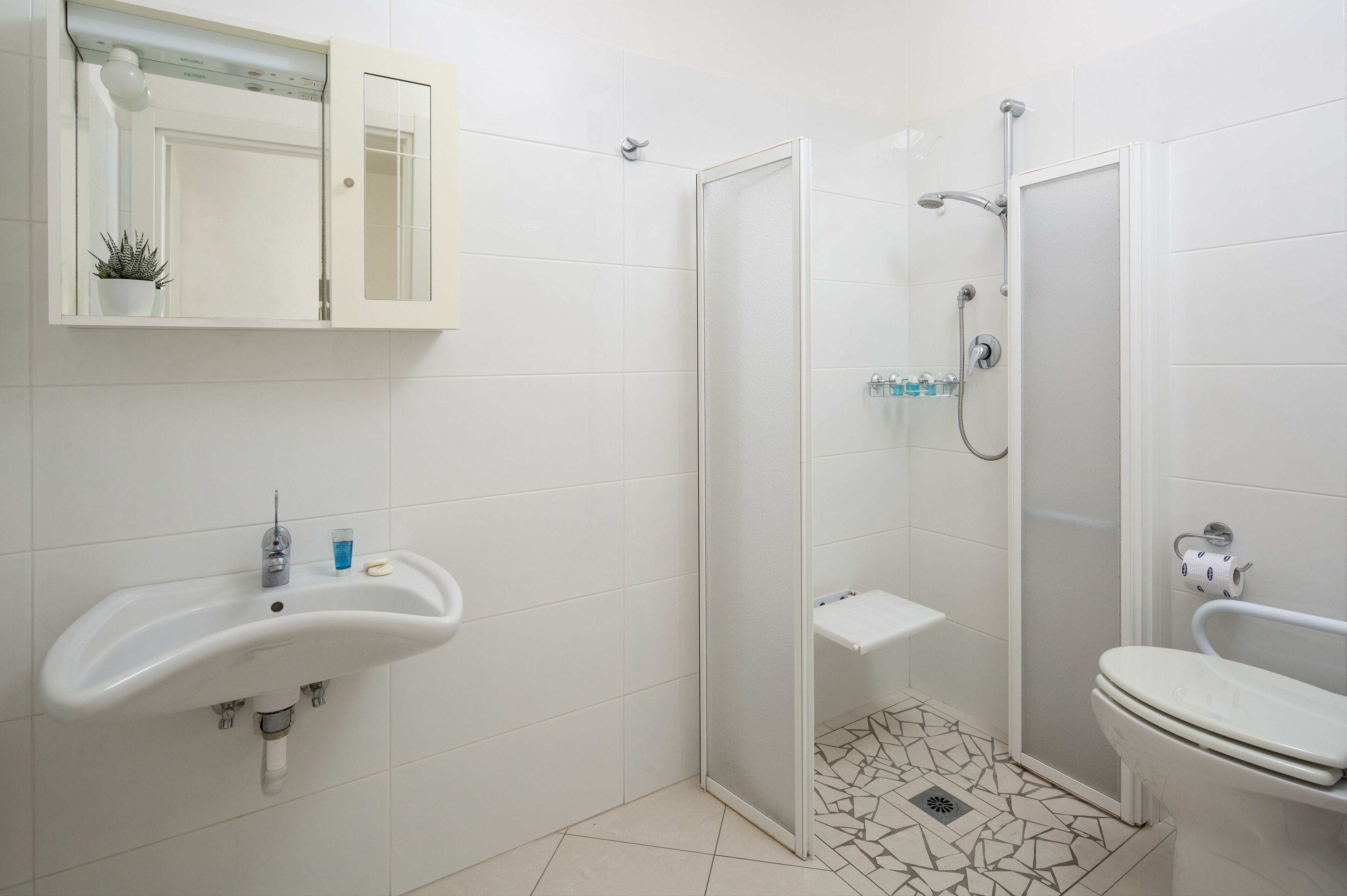 A bathroom with a white sink, toilet, and shower area.