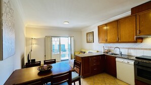 Une cuisine avec des meubles de rangement en bois, un four encastré et un coin repas comprenant une table et des chaises.