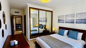 Une chambre d’hôtel avec un grand lit, un bureau avec une chaise, un miroir et des œuvres d’art accrochées au mur.