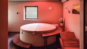 A circular hot tub with wooden benches, a window with blinds, a clock, and a small potted plant. - Beautiful home in Kanfanar with sauna (Kanfanar)