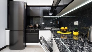 A modern kitchen with a black refrigerator, stainless steel appliances, a granite countertop, and a black backsplash. - Stay Inn on 33.1 Mashtots Ave. (Yerevan)