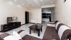 A modern living room with a sofa set, a TV, a coffee table, and a kitchen in the background. - Stay Inn on 33.1 Mashtots Ave. (Yerevan)