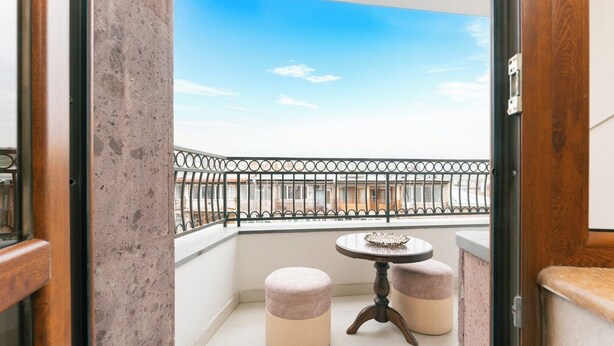 A balcony with a metal railing, a small round table, and two cushioned stools. - Stay Inn on 33.1 Mashtots Ave. (Yerevan)