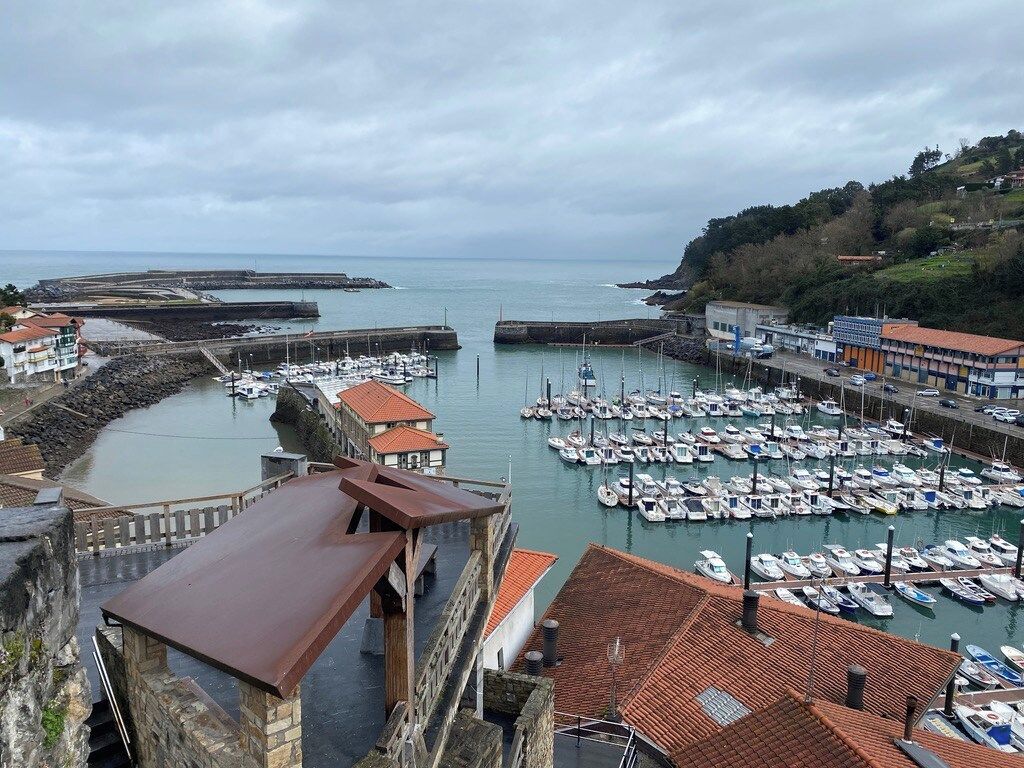 Un pueblo costero con un puerto deportivo, edificios de piedra y vistas al mar.