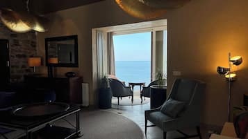 A living room with a view of the sea, a fireplace, and a large window.