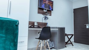 Une chambre d’hôtel compacte dotée d’une kitchenette, d’un téléviseur fixé au mur et d’un petit espace bureau.