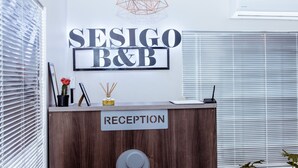 Un comptoir d’accueil avec une pancarte indiquant « RÉCEPTION » et une autre pancarte au-dessus, sur laquelle on peut lire « SEIGO B&B ».
