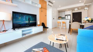 A modern living room with a flat-screen TV, a coffee table, and a blue sofa. - Macy Apartment - Tresor Sai Gon Downtown (Ho Chi Minh City)