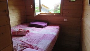 Een kleine houten kamer met een enkel bed, een raam en een deur.