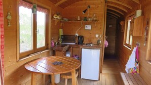 Een gezellig houten chalet met een keukenhoek, inclusief een houten tafel, een spoelbak en een koelkast.