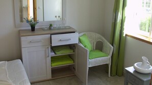 Ein kleines, ordentliches Badezimmer mit Spiegel, Waschbecken und Stuhl.