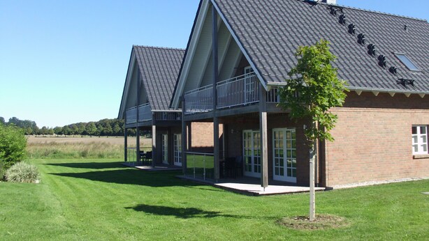 Ein modernes Haus mit geneigtem Dach, großen Fenstern und einem Balkon.