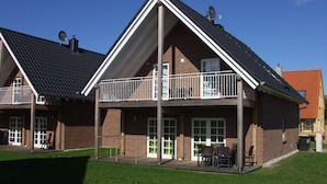 Ein zweistöckiges Gebäude mit Balkon, überdachter Terrasse und einer Ziegel-Fassade.