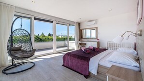 Un dormitorio moderno con cama, una silla colgante, un escritorio y un ventanal grande.
