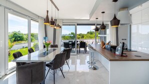 Una cocina moderna con una isla grande, iluminación colgante y vistas al exterior.