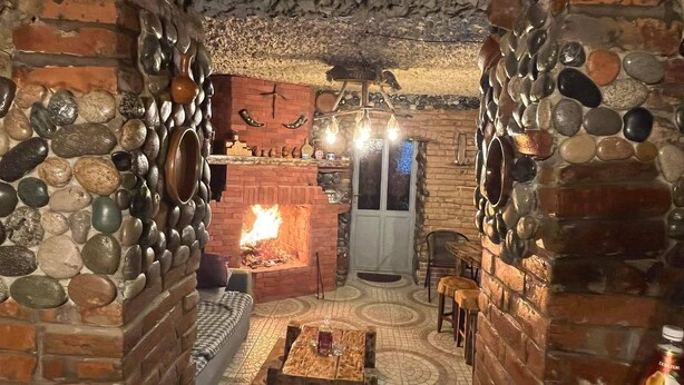 A cozy interior with a stone wall, a fireplace, and a patterned floor.