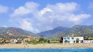 A coastal property with a beach, mountains, and a clear sky. - Blue - Beach Front Spectacular Villa Sleeps 10 (Agia Marina Chrysochous)