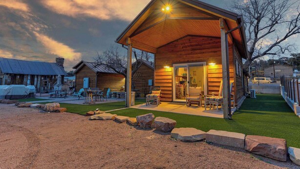A rustic wooden cabin with a covered porch, outdoor seating, and a well-maintained lawn. - Adventure Cabin within the Heart of Arizona! Pickle ball court! (Payson)