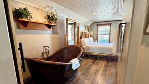 A room with a large wooden bathtub, wooden flooring, and a bed with a wooden headboard. - Adventure Cabin within the Heart of Arizona! Pickle ball court! (Payson)