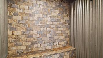 A brick wall with a metal door and a wooden bench.