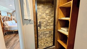 A bathroom with a glass shower door, wooden shelving, a towel hanging on the wall, and a wooden floor. - Adventure Cabin within the Heart of Arizona! Pickle ball court! (Payson)