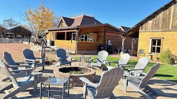 A patio area with Adirondack chairs and a fire pit, surrounded by wooden cabins with a covered porch.