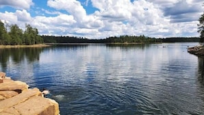 Un lac paisible, avec une jetée en pierre sur la gauche et une rive bordée d’arbres.
