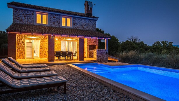 A stone house with a swimming pool, outdoor seating, and a patio area.