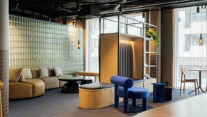 Un área de estar moderna con un sofá modular, una mesita de centro redonda, un sillón azul y una pequeña mesita auxiliar.