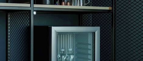 A compact refrigerator with a clear door, containing two bottles of water, and a coffee machine on the upper shelf.