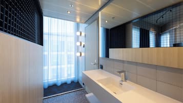 A modern bathroom with a large mirror, a white sink, and a shower area.