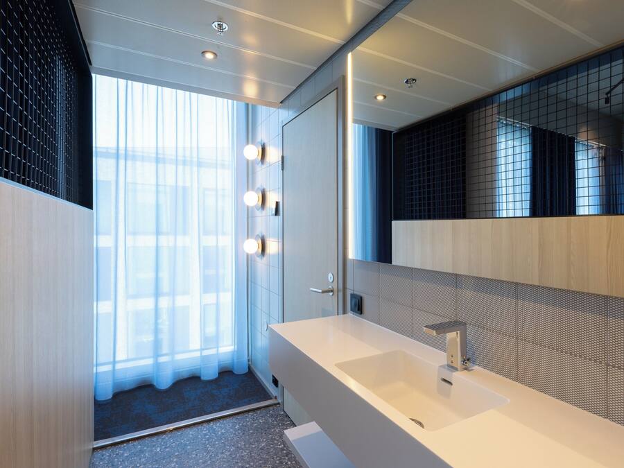 A modern bathroom with a large mirror, a white sink, and a shower area.