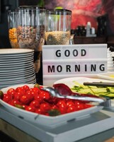 En frukostbuffé med ett varierat utbud av mat och en skylt med texten ”God morgon”.