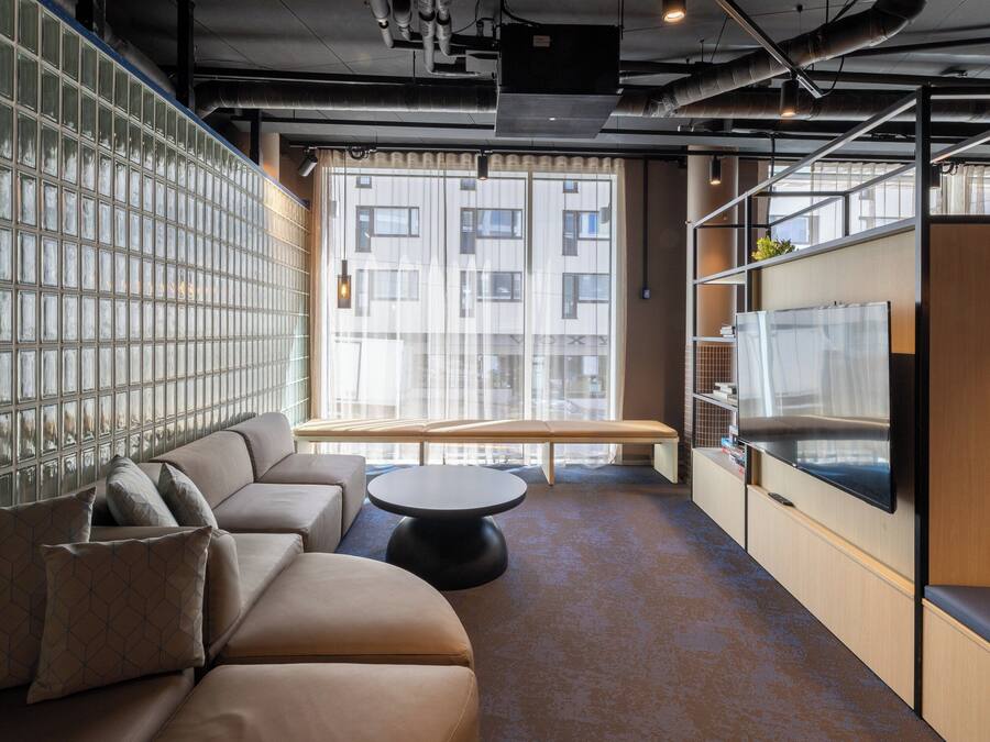 A modern lounge area with a sofa, a round table, and a TV screen.