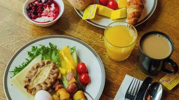 A breakfast tray with croissants, eggs, tomatoes, cucumbers, and a bowl of berries.
