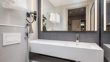 Une salle de bain moderne avec un lavabo blanc, un grand miroir et un porte-serviettes.