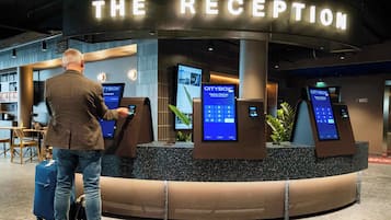 A reception area with a sign reading "THE RECEPTION" and multiple CityBox self-service kiosks for check-in and check-out.