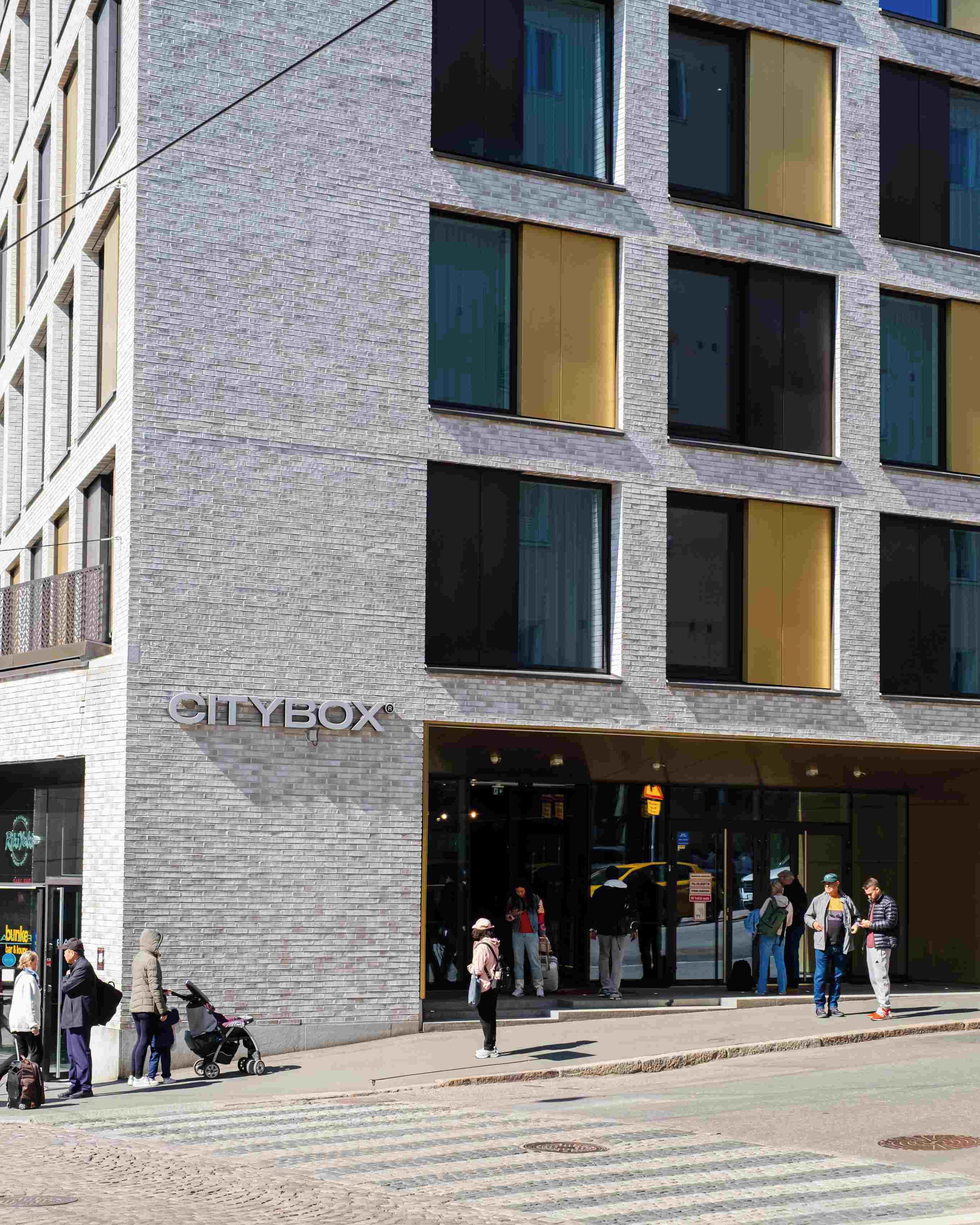 Un edificio moderno con un letrero que dice 'CITYBOX', con fachada de ladrillo y ventanas amplias.