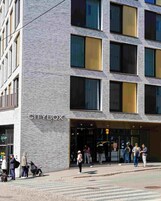 Un edificio moderno con un letrero que dice 'CITYBOX', con fachada de ladrillo y ventanas amplias.