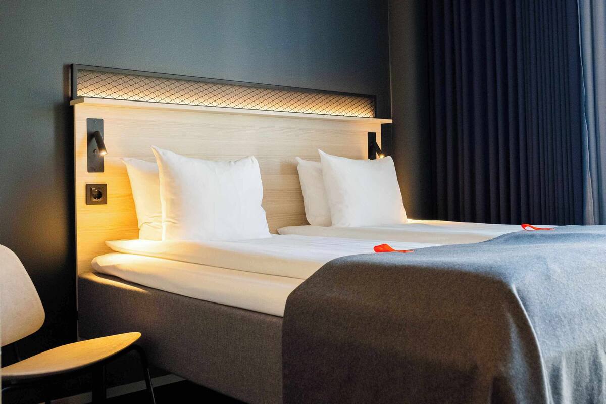 A hotel room with a bed, a chair, and a window with curtains.
