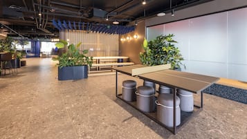 Un espacio de oficina moderno con una mesa grande, varias sillas, plantas en macetas y una pizarra blanca de gran tamaño en la pared.
