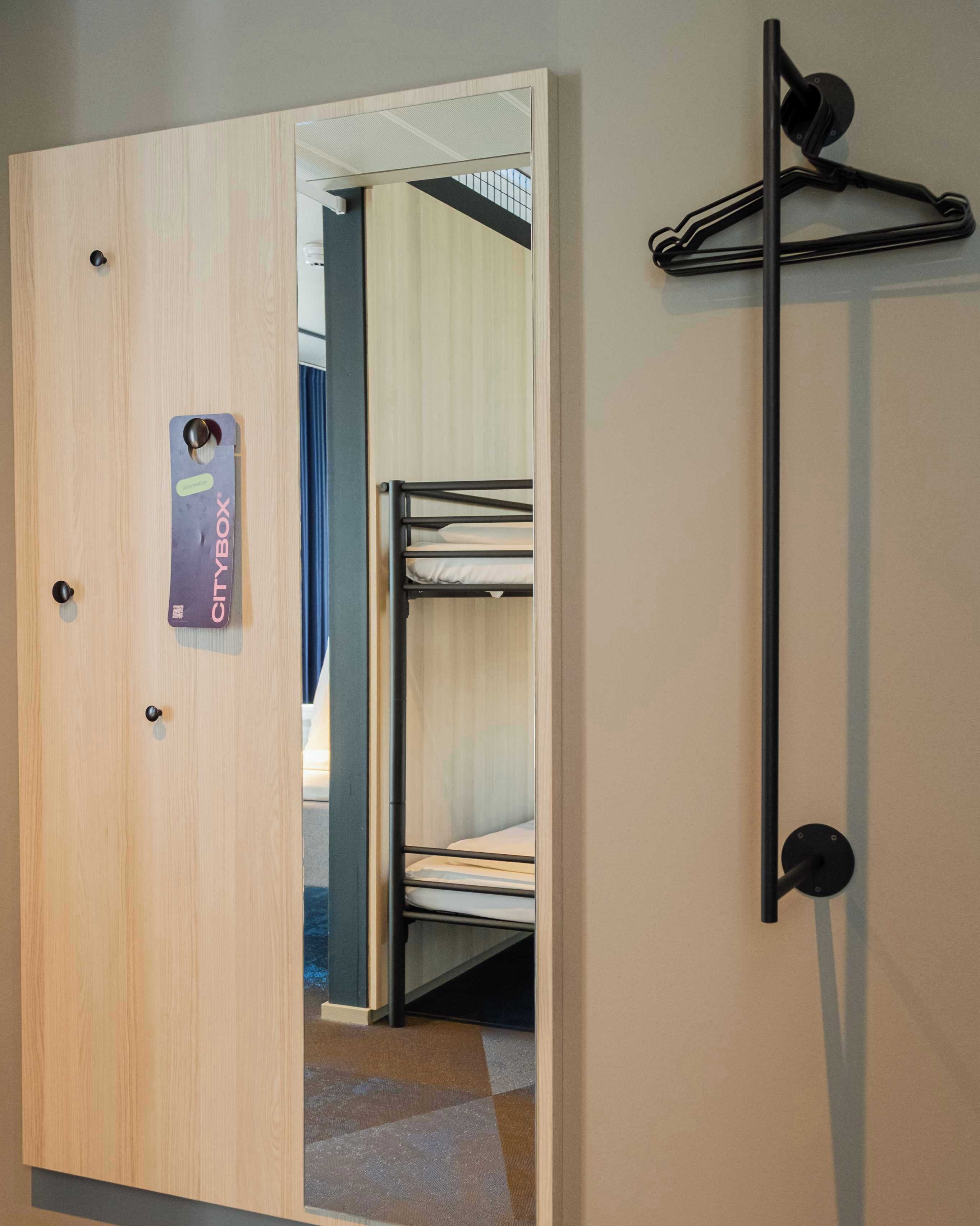 A hotel room with a CityBox luggage storage system, a bunk bed, and a coat rack.