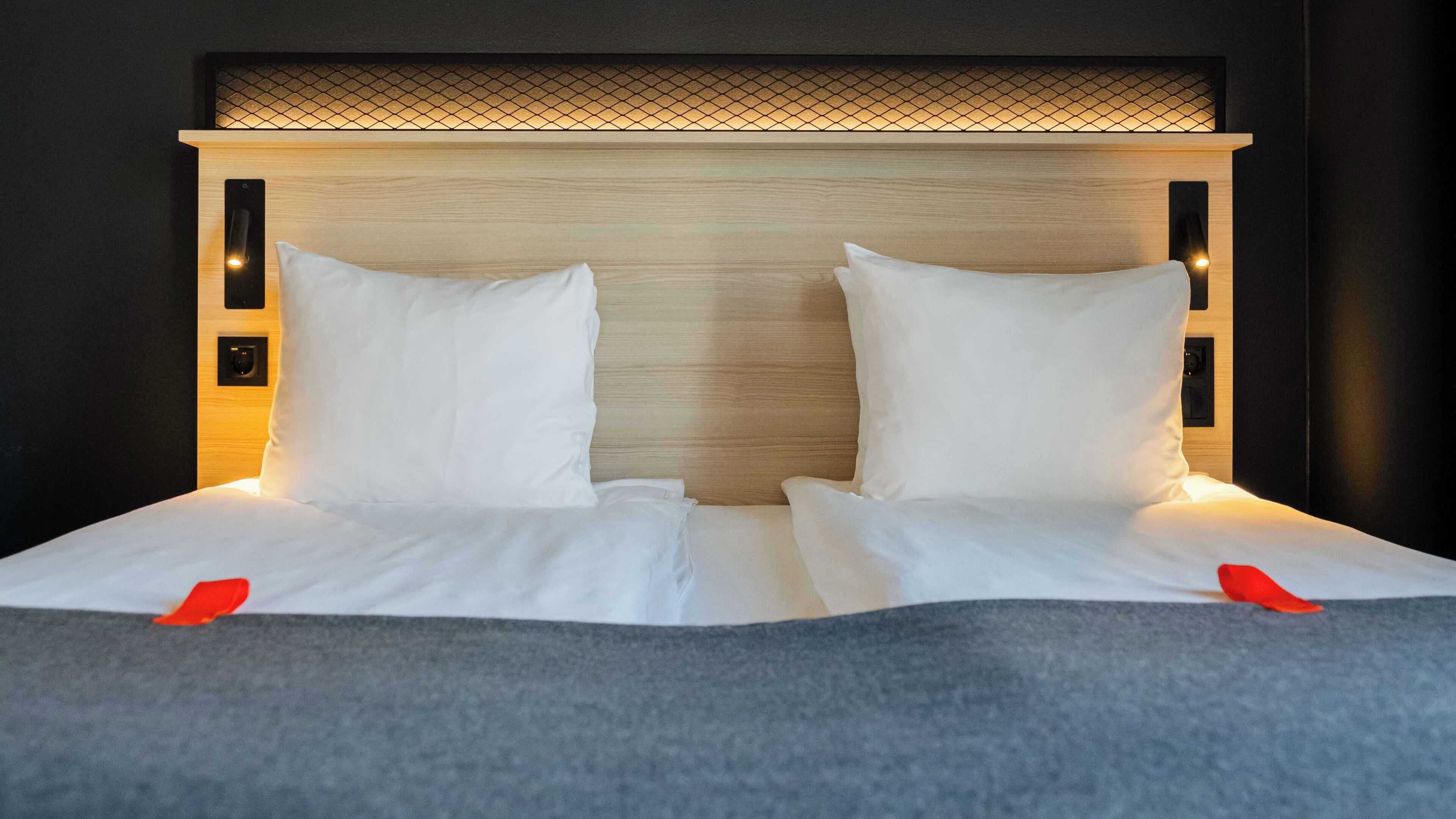 A neatly made bed with white linens and pillows, a wooden headboard with a grid pattern, and two bedside lamps.
