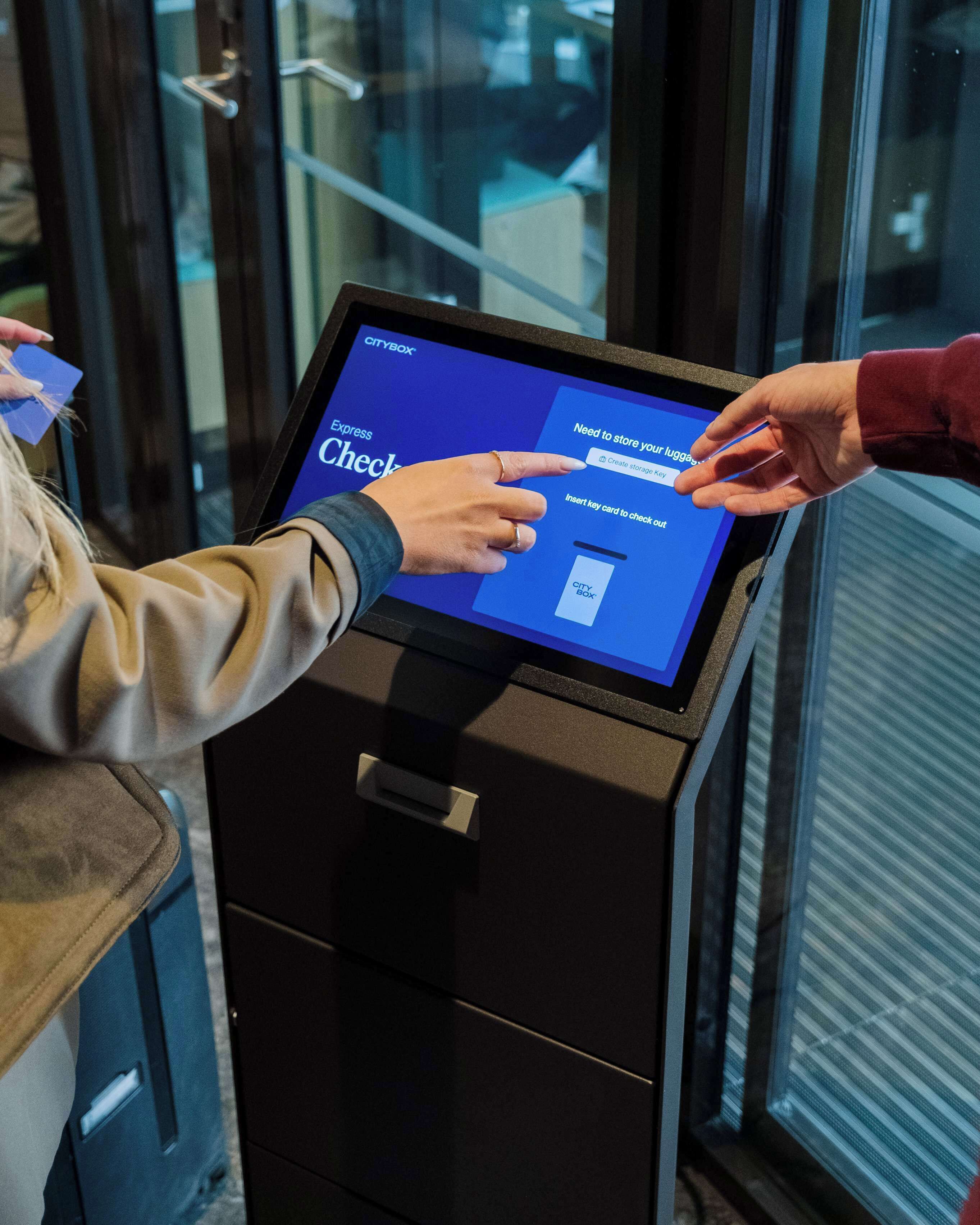 Una persona che interagisce con un chiosco digitale, probabilmente per effettuare il check-in o accedere ai servizi.