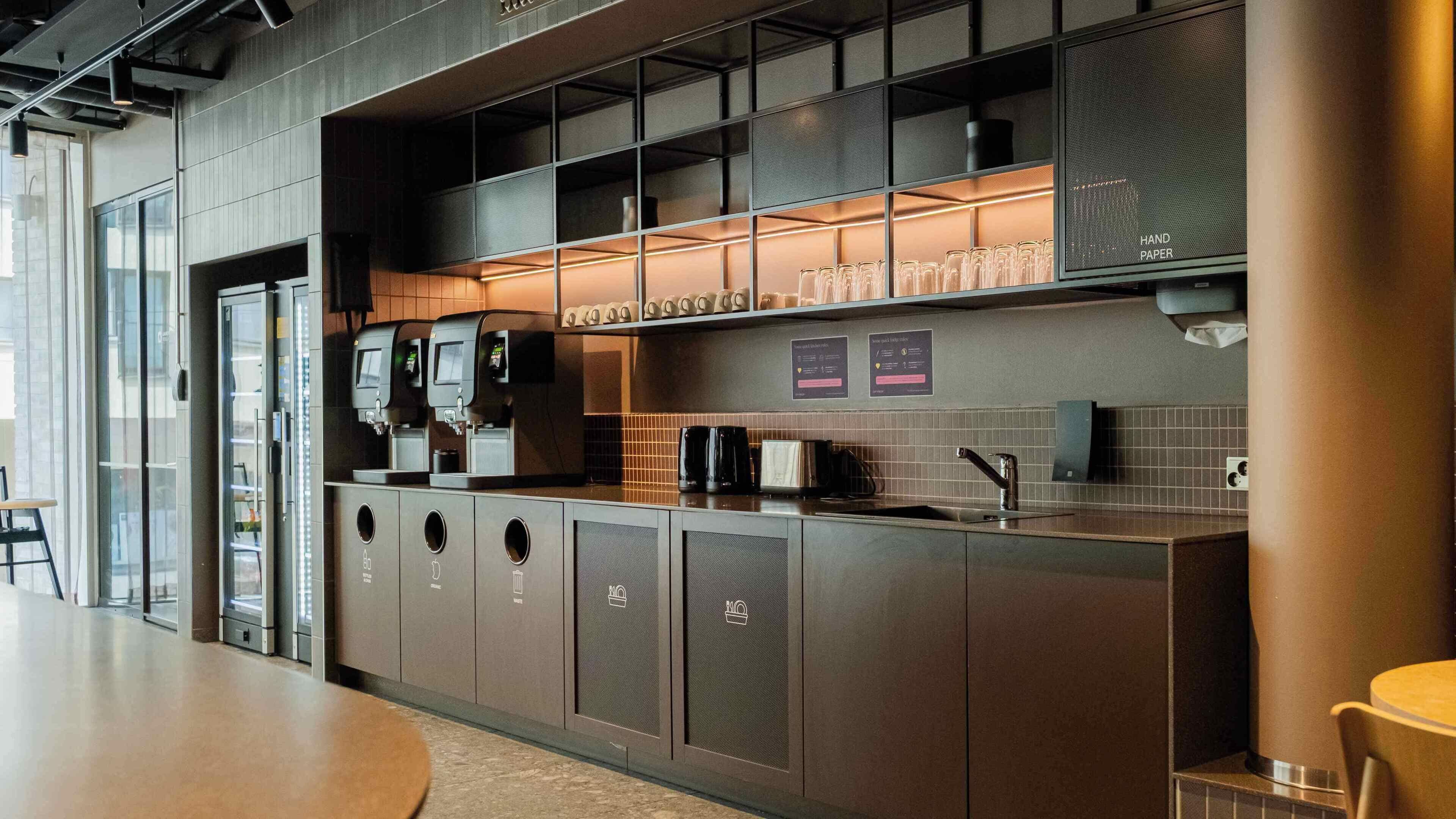 Una cocina moderna con una estación de café, un lavamanos y una vitrina de vidrio.