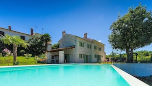 A large swimming pool with a stone building in the background. - Cozy home in Rakotule (Rakotule)