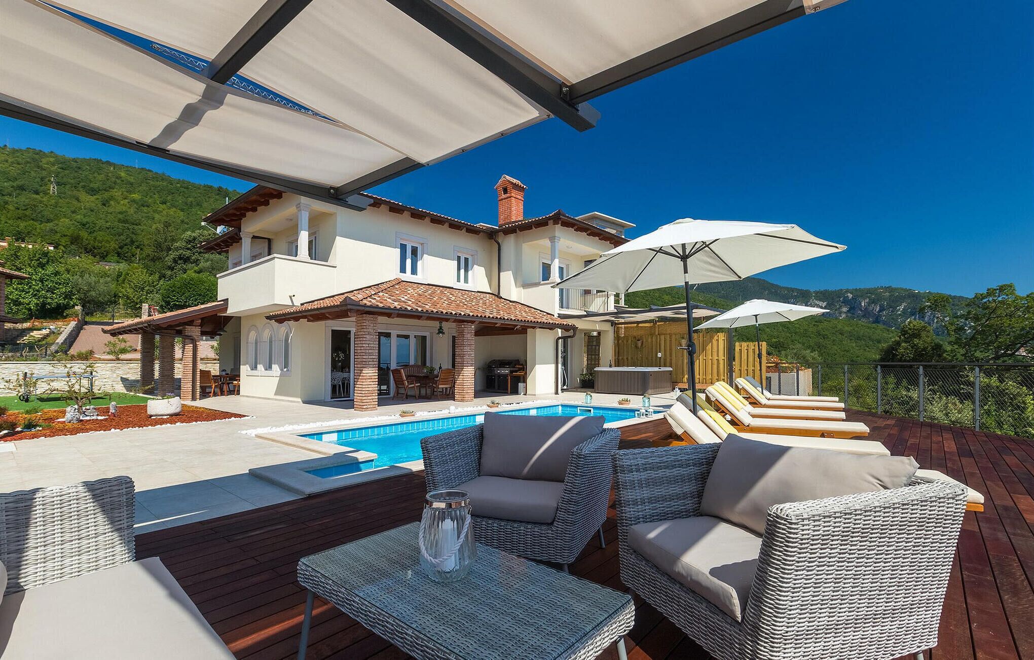 Une villa moderne dotée d’une piscine, d’un espace extérieur aménagé et offrant une vue sur les montagnes.