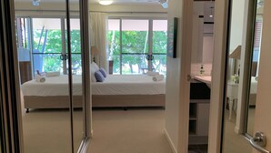 A bedroom with a bed, a window, and a bathroom visible through an open door. - BHA 1 Beachfront Haven - 2 bedroom (Mission Beach)